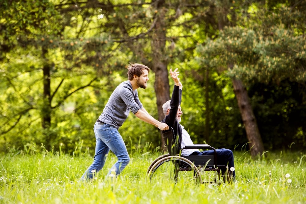 Wheeled Devices man pushing his father in a wheel chair through a field